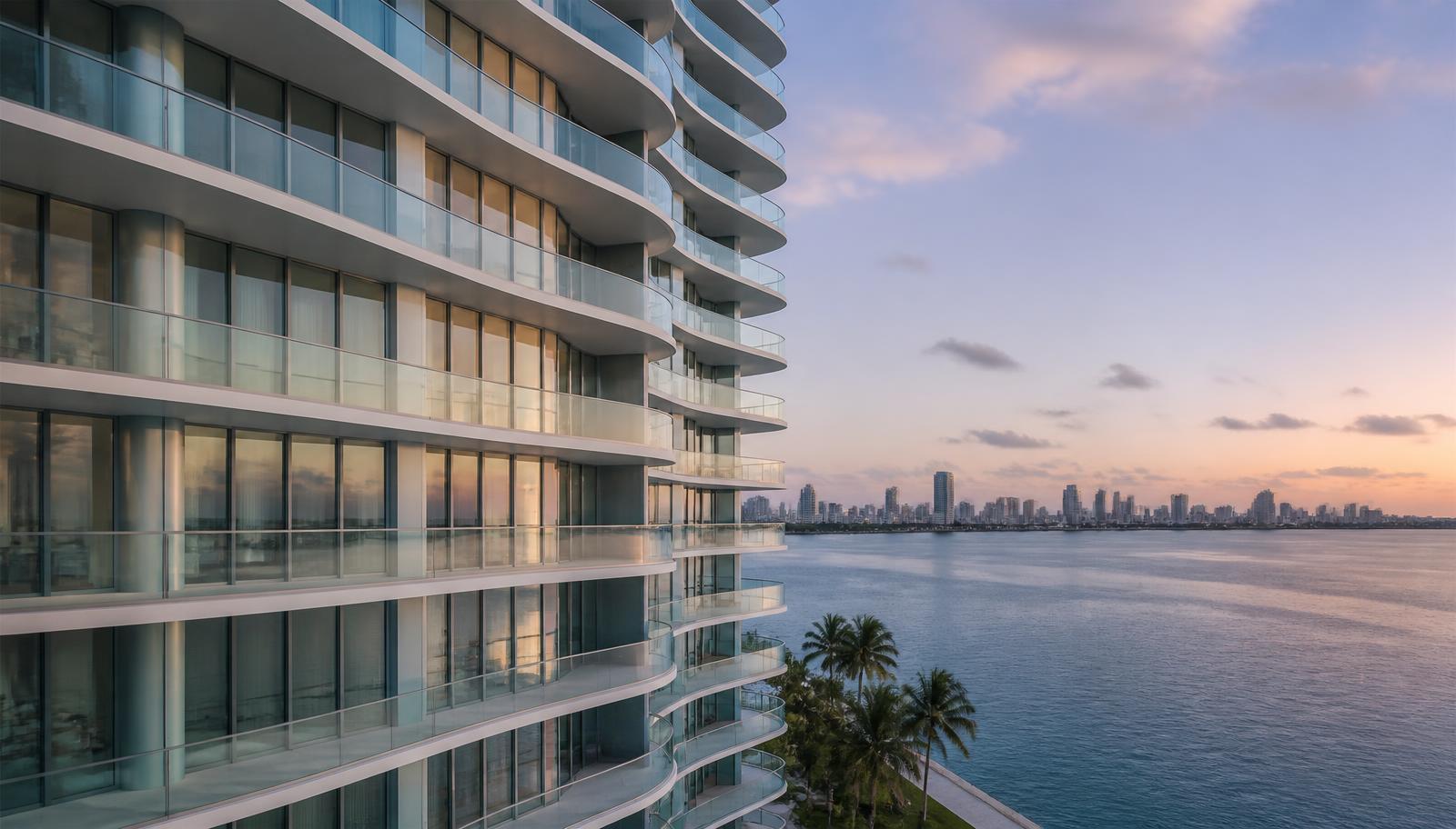 Modern Miami bayfront condominium tower with curved glass balconies at dusk