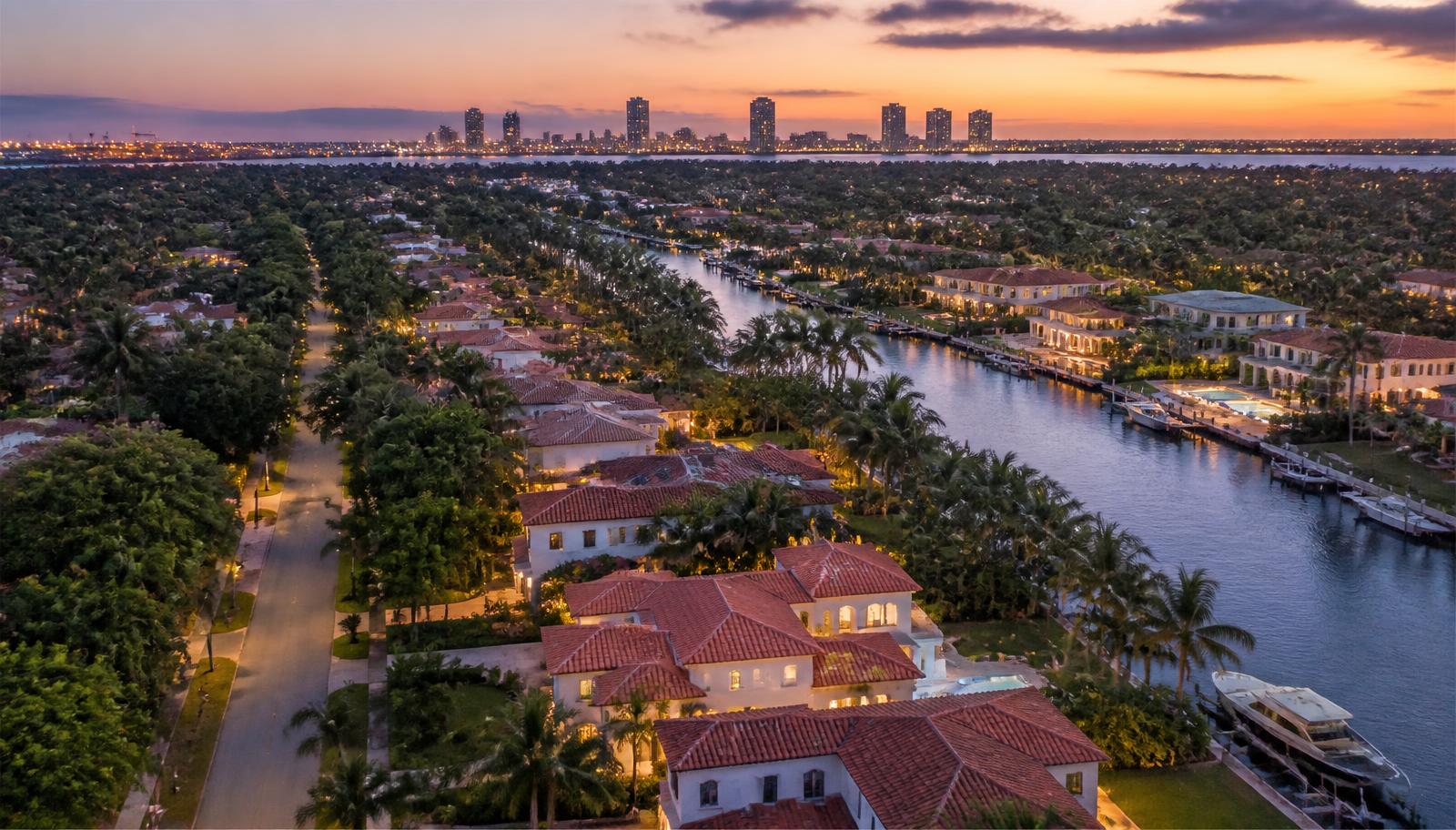 Vecindario residencial de Miami con casas frente al agua, vegetación tropical y el skyline al fondo